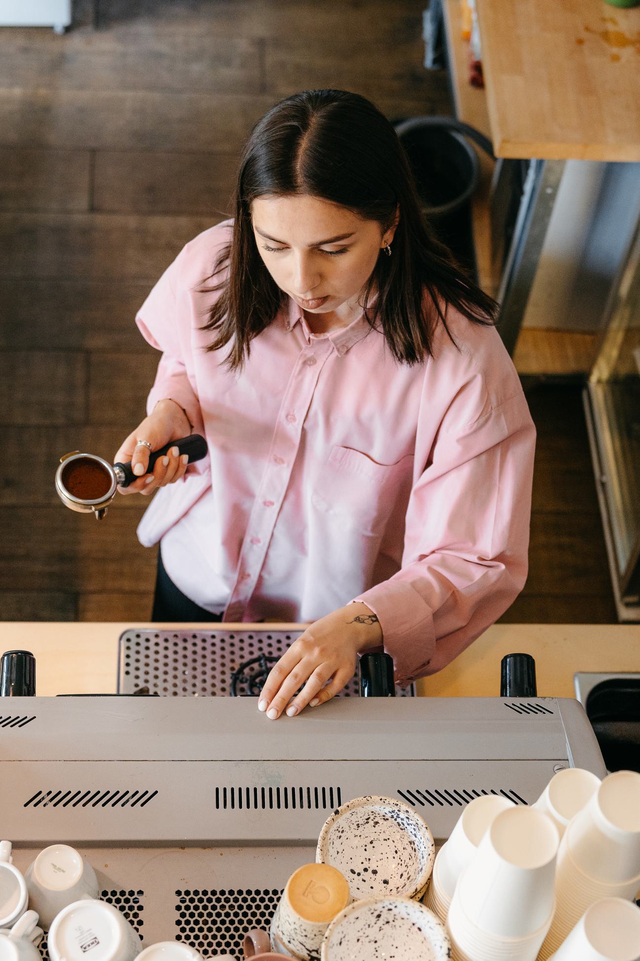 A barista working in a modern coffee shop, viewed from overhead.